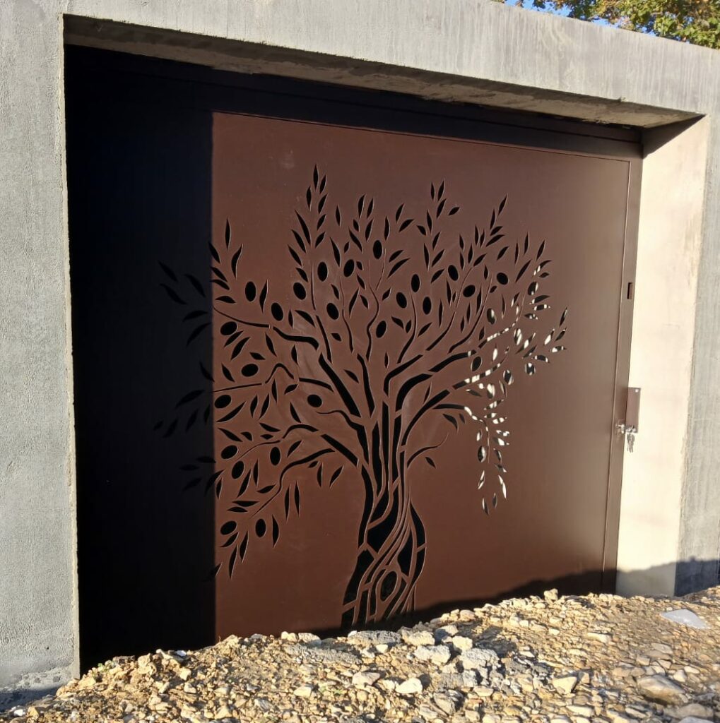 Porte de service du local piscine, coulissante sur rail haut, avec décor « Olivier » découpé au laser.