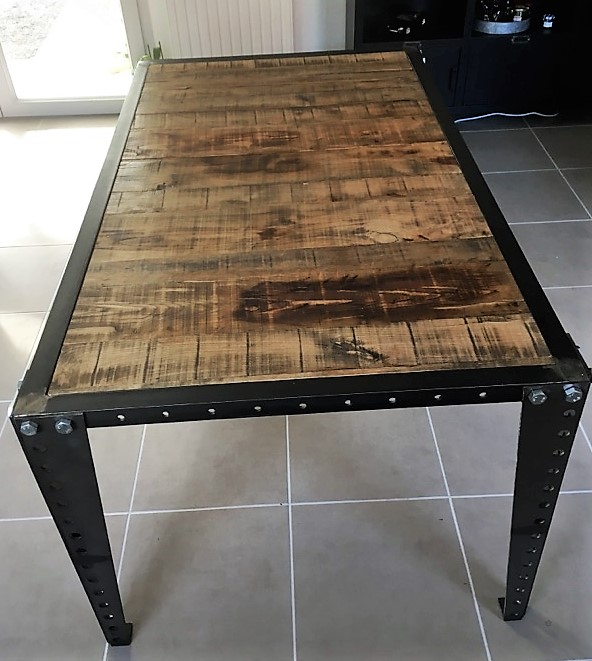 Table rustique : structure en acier découpée au laser, boulonnage apparent, plateau en châtaignier brut.
